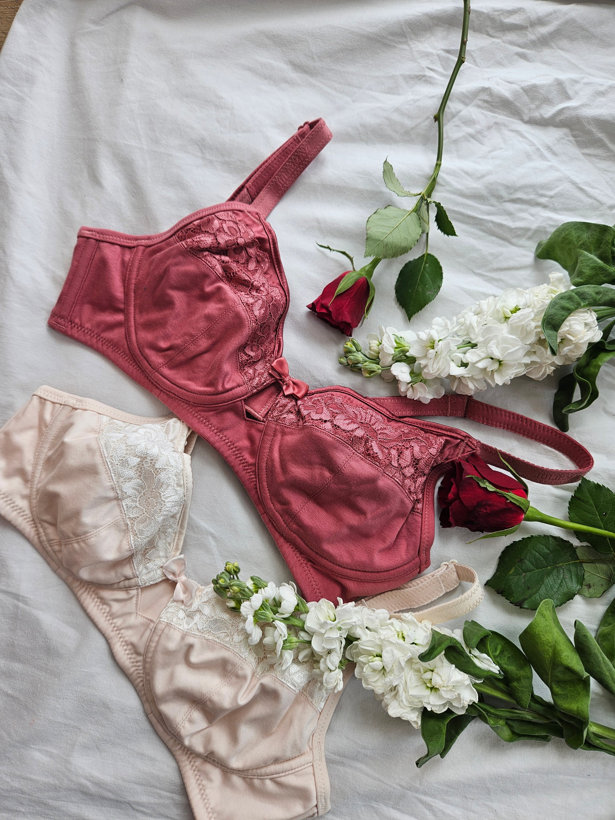 Flat lay of a dusky-pink organic cotton bra and set with roses – JulieMay Lingerie