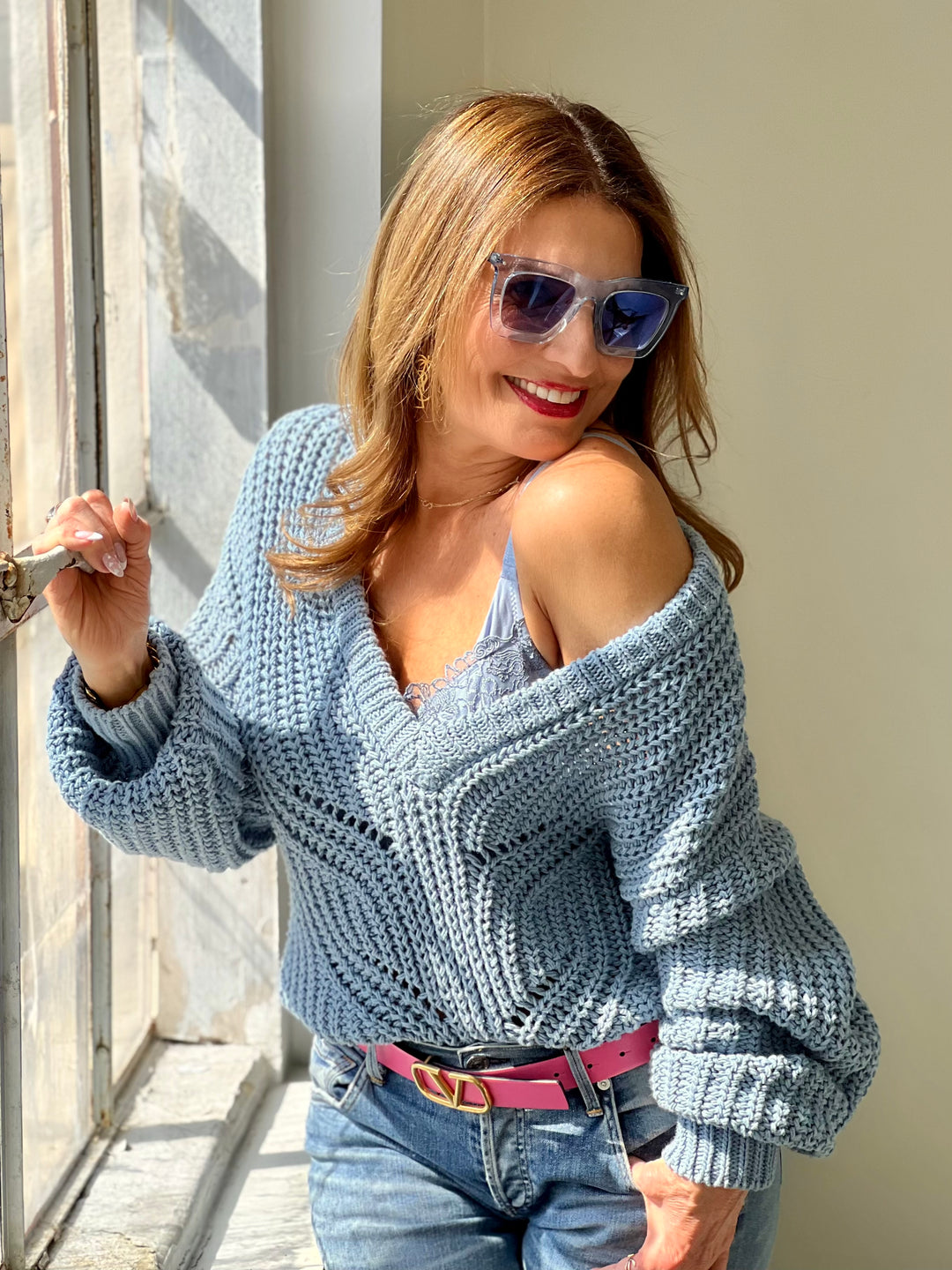 Woman in a blue cardigan and sunglasses with lace lingerie underneath